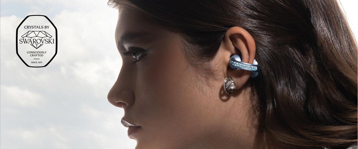 Profil kobiety noszącej słuchawki moto buds loop typu open-ear w kolorze Cloud Dancer ozdobione kryształkami Swarovski